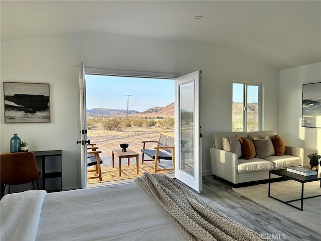 bedroom with lofted ceiling, wood finished floors, a mountain view, and access to exterior
