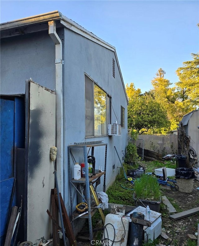 view of side of property featuring cooling unit, stucco siding, and fence