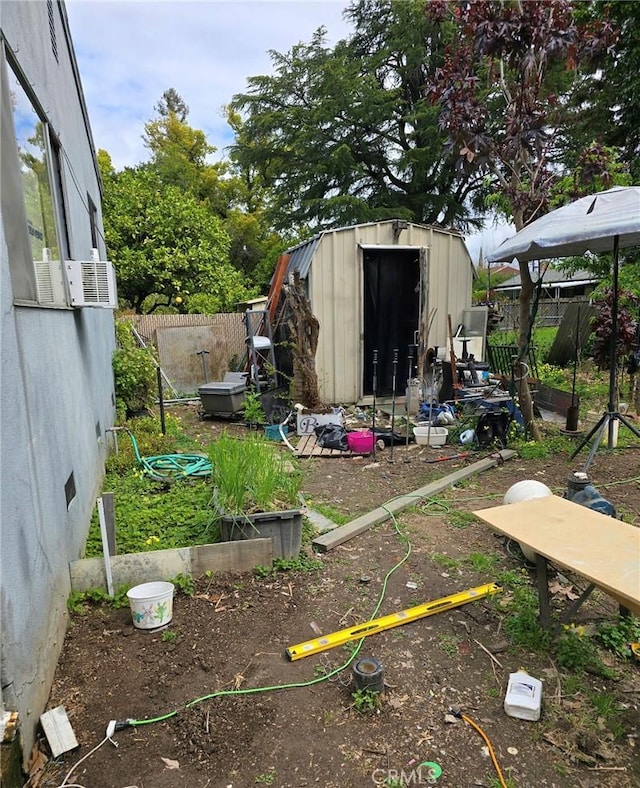 view of yard featuring an outdoor structure, fence, a storage unit, and a garden