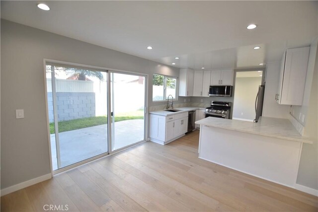 23408 Dorset Pl, Harbor City, CA 90710 - kitchen with white cabinets, light wood-style floors, appliances with stainless steel finishes, and a sink