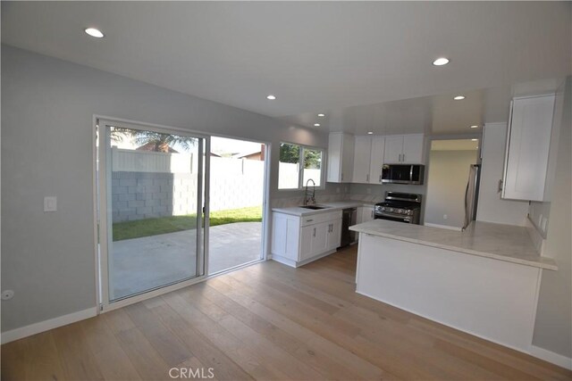 23408 Dorset Pl, Harbor City, CA 90710 - kitchen featuring light wood finished floors, a sink, white cabinetry, light countertops, and appliances with stainless steel finishes