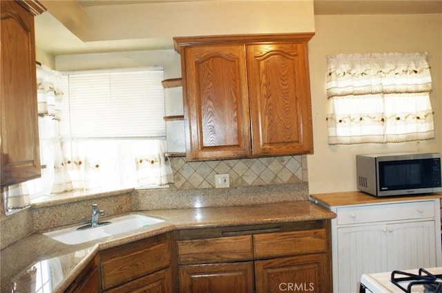 3724 W 105th St, Inglewood, CA 90303 - kitchen featuring stainless steel microwave, tasteful backsplash, brown cabinetry, and light countertops