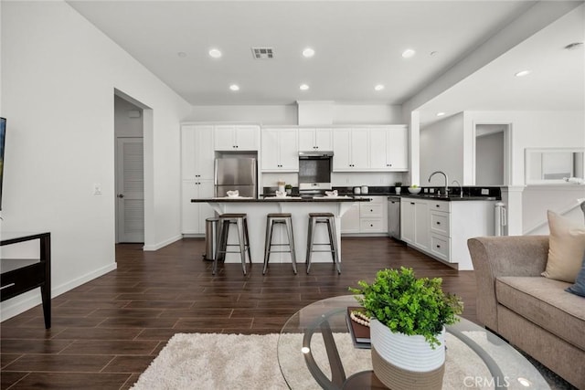 144 Borrego, Irvine, CA 92618 - kitchen with a breakfast bar, a kitchen island, dark countertops, visible vents, and appliances with stainless steel finishes