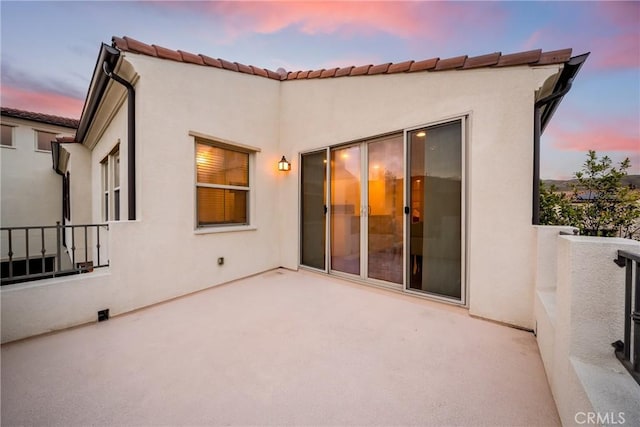 144 Borrego, Irvine, CA 92618 - back of property at dusk with a tile roof, a balcony, stucco siding, and a patio area