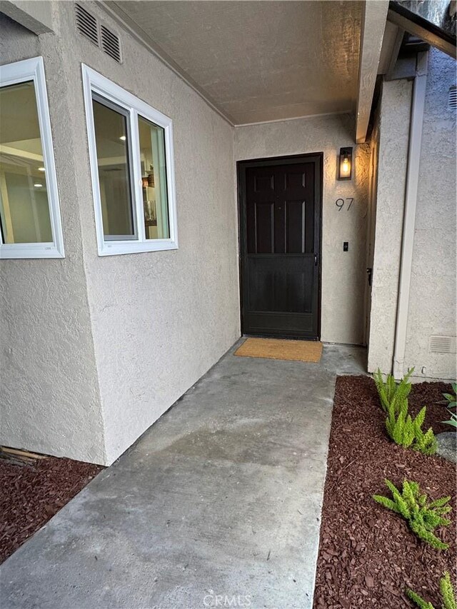 entrance to property with stucco siding and visible vents