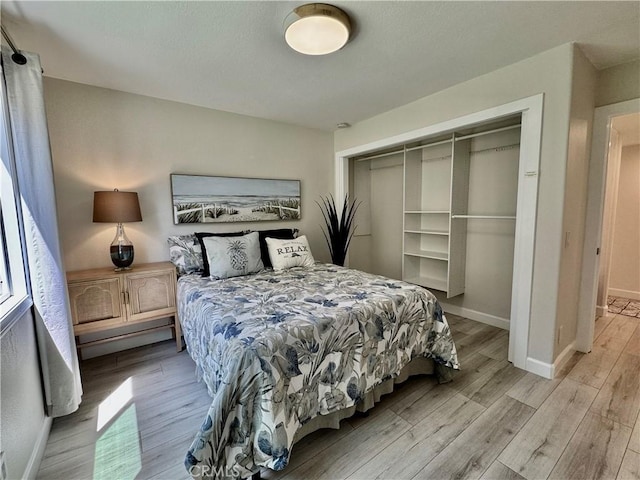 bedroom featuring baseboards, light wood finished floors, and a closet
