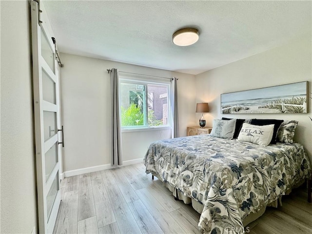 28181 Sorrento Unit 97, Laguna Niguel, CA 92677 - bedroom with light wood-type flooring, a barn door, baseboards, and a textured ceiling