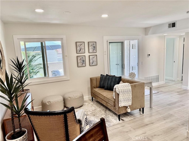 living room with baseboards, light wood finished floors, and visible vents