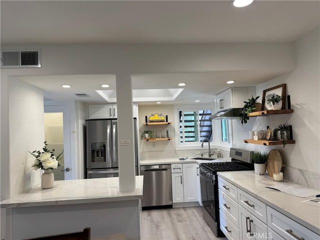 kitchen featuring light stone counters, stainless steel appliances, open shelves, visible vents, and a sink