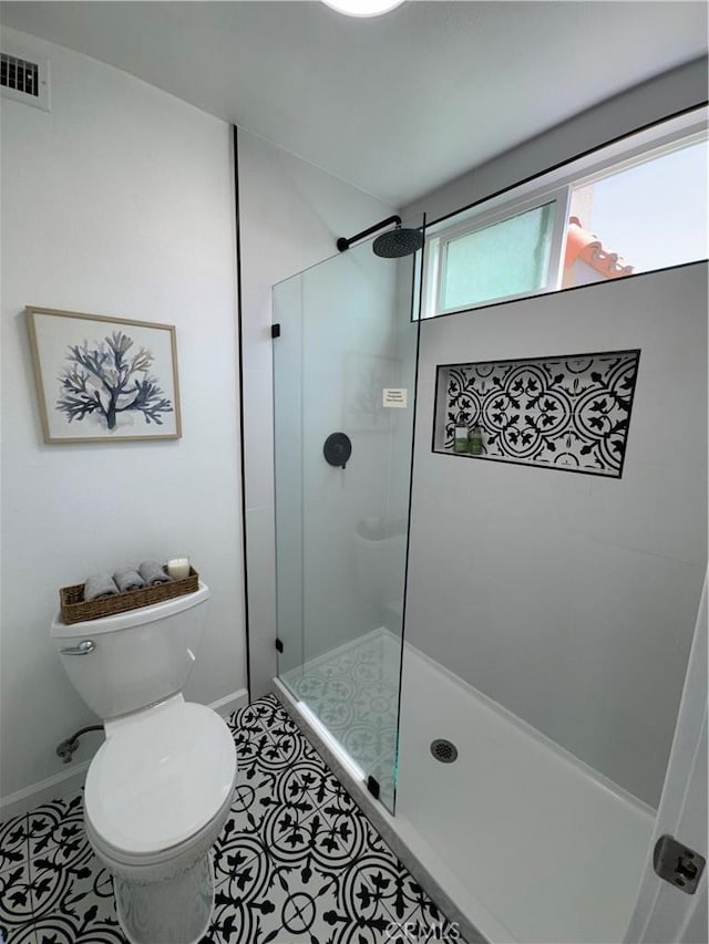 bathroom with tile patterned floors, baseboards, a tile shower, toilet, and visible vents