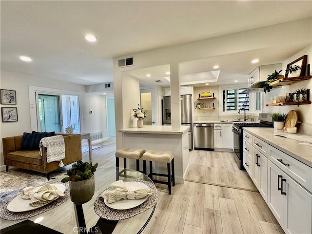 kitchen with light wood finished floors, open shelves, visible vents, appliances with stainless steel finishes, and white cabinetry