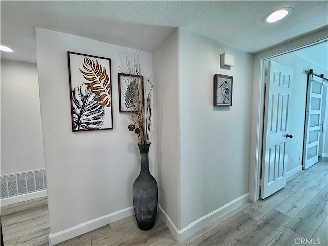 28181 Sorrento Unit 97, Laguna Niguel, CA 92677 - hall featuring a barn door, wood finished floors, baseboards, recessed lighting, and a textured ceiling