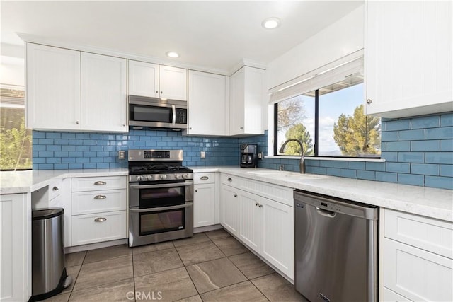 kitchen featuring white cabinets, stainless steel appliances, recessed lighting, a sink, and backsplash