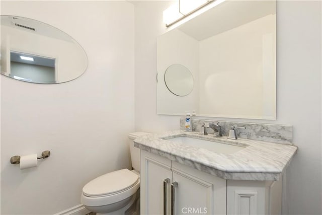 bathroom with toilet, vanity, and baseboards