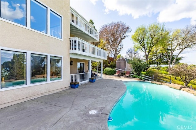 outdoor pool with a patio, an outbuilding, and a storage shed