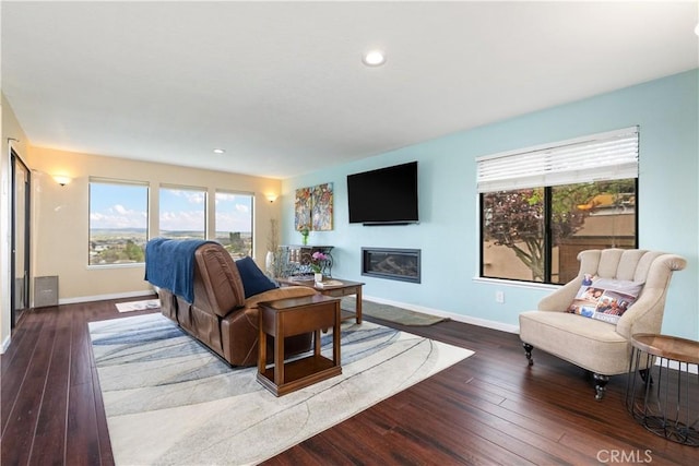 living area featuring baseboards, recessed lighting, hardwood / wood-style flooring, and a glass covered fireplace