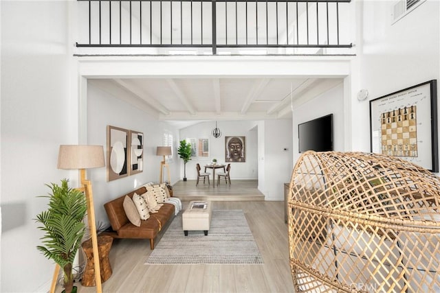 living room featuring visible vents, beam ceiling, and wood finished floors