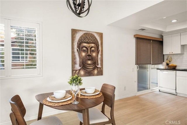 dining room featuring recessed lighting, an inviting chandelier, baseboards, a raised ceiling, and light wood finished floors
