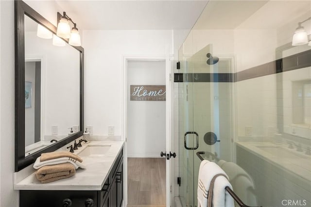 bathroom with vanity, a stall shower, and wood finished floors