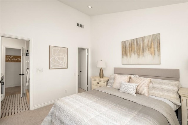 bedroom with a walk in closet, carpet, baseboards, a high ceiling, and visible vents