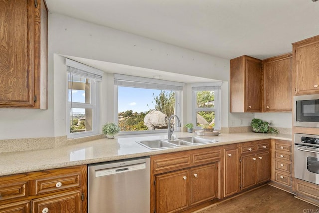kitchen with dark wood-type flooring, a sink, stainless steel appliances, and brown cabinets