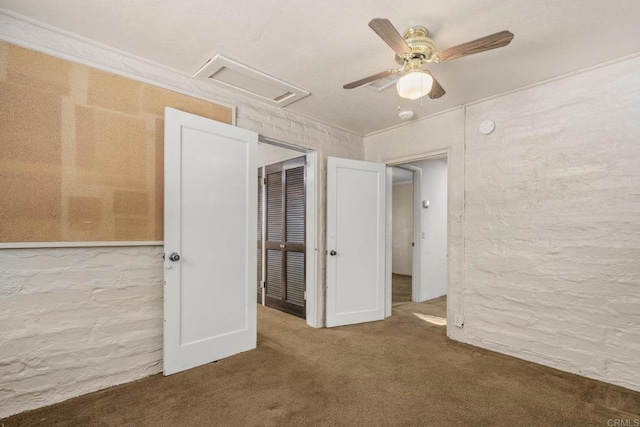 unfurnished bedroom featuring a ceiling fan, carpet floors, and attic access