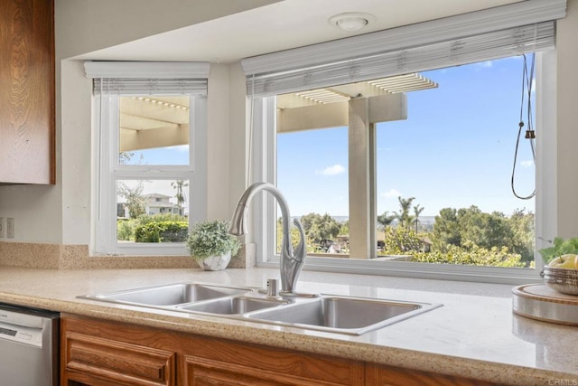 kitchen with dishwashing machine, a sink, plenty of natural light, and brown cabinets