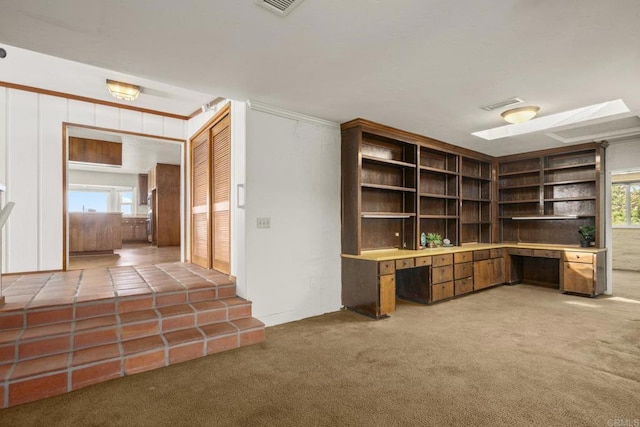unfurnished office featuring built in study area, visible vents, crown molding, and light colored carpet