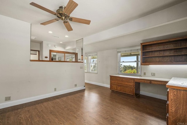 unfurnished office with baseboards, ceiling fan, dark wood-type flooring, and built in study area
