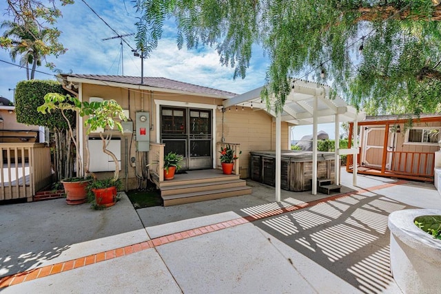 back of house with a hot tub, fence, and a patio area