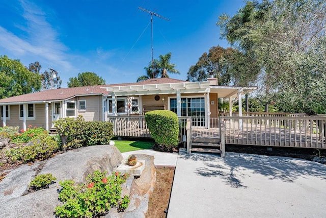 view of front of property with a pergola, a chimney, and a wooden deck