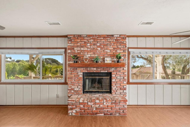 unfurnished living room with a fireplace, visible vents, and wood finished floors