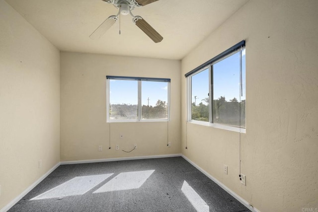 carpeted spare room featuring baseboards and ceiling fan