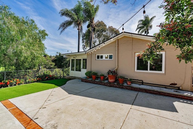 back of house featuring a patio, a yard, fence, and stucco siding