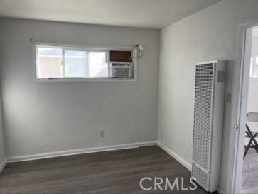 410 N San Jacinto St, Hemet, CA 92543 - spare room with baseboards, a heating unit, and dark wood-type flooring