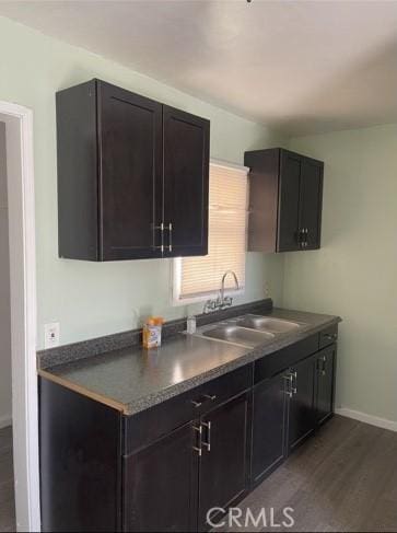 410 N San Jacinto St, Hemet, CA 92543 - kitchen with dark wood-style flooring, a sink, dark countertops, and baseboards