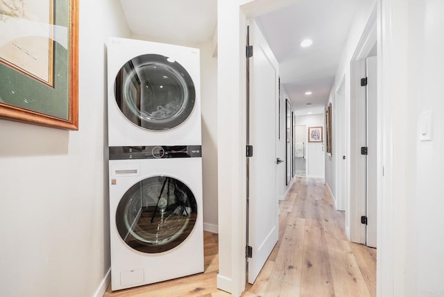 clothes washing area featuring stacked washer and clothes dryer, laundry area, baseboards, light wood-style floors, and recessed lighting