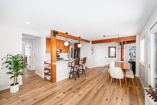 kitchen featuring light countertops, light wood-style flooring, high end fridge, a sink, and a breakfast bar area