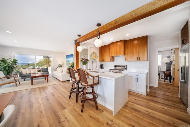 kitchen featuring light countertops, custom range hood, stainless steel appliances, a sink, and light wood-style floors