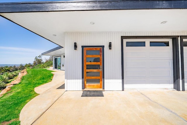 view of exterior entry with driveway and a garage