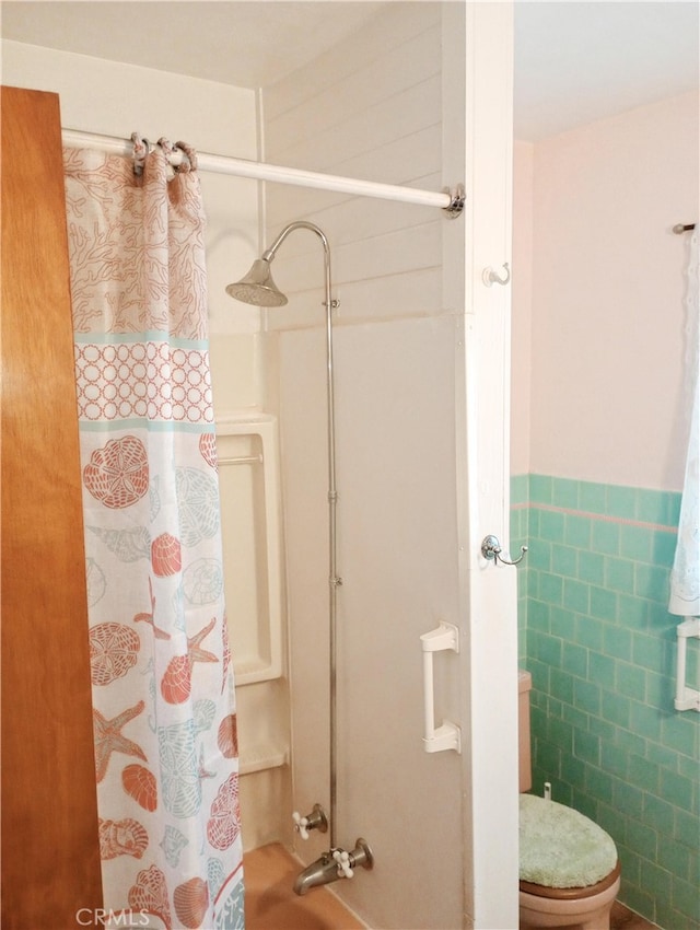 bathroom with shower / tub combo, wainscoting, tile walls, and toilet