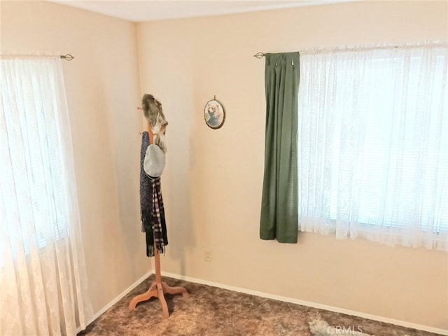 carpeted empty room featuring baseboards