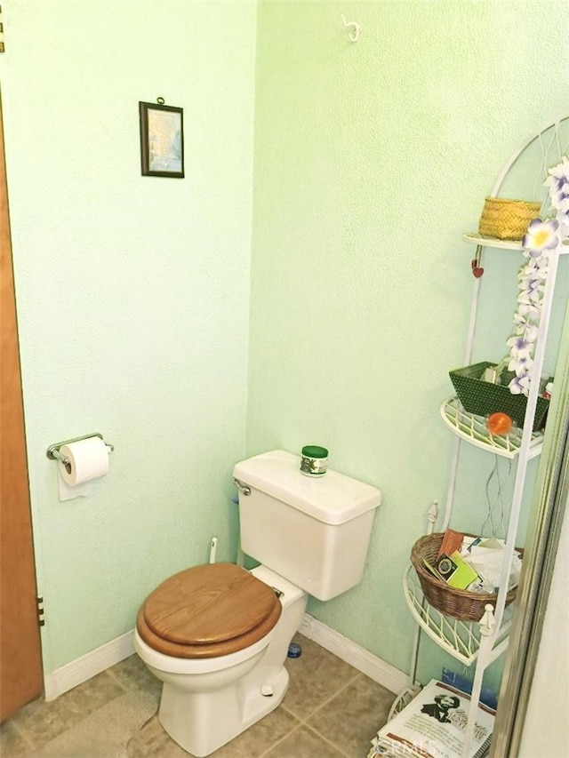 bathroom featuring tile patterned flooring, baseboards, and toilet