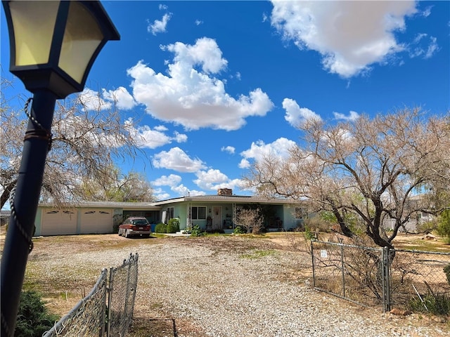 view of front of property featuring driveway, a chimney, fence, and an attached garage