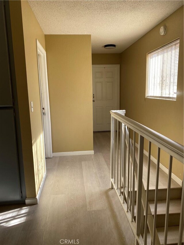 698 W Phillips Blvd, Pomona, CA 91766 - hallway with an upstairs landing, a textured ceiling, baseboards, and wood finished floors