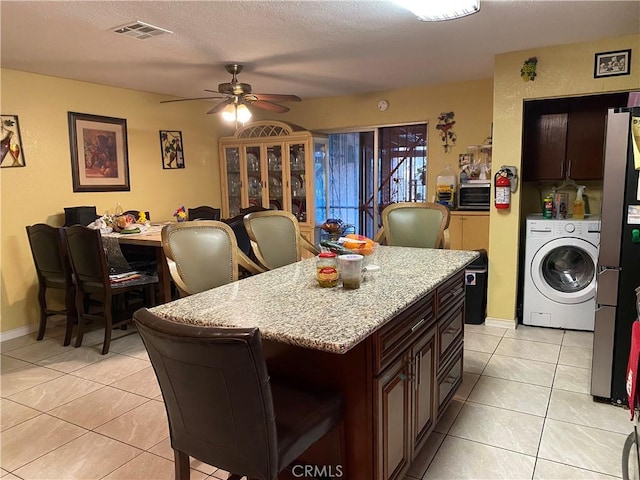 698 W Phillips Blvd, Pomona, CA 91766 - kitchen featuring visible vents, washer / clothes dryer, ceiling fan, light tile patterned floors, and freestanding refrigerator