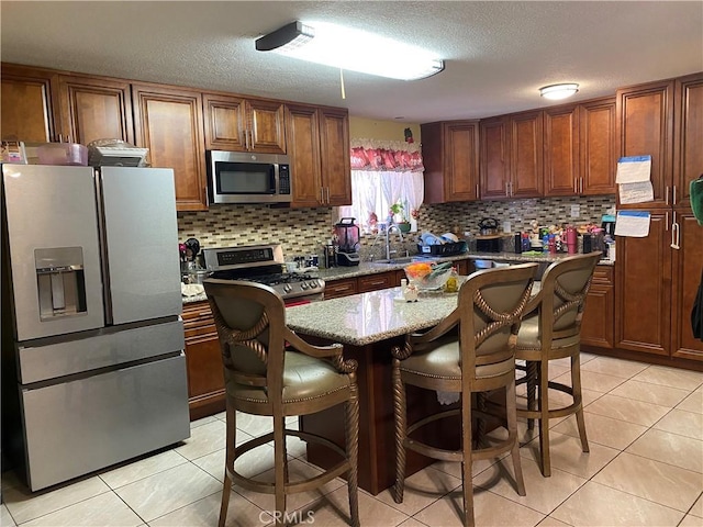 698 W Phillips Blvd, Pomona, CA 91766 - kitchen with a sink, light stone countertops, tasteful backsplash, appliances with stainless steel finishes, and light tile patterned floors