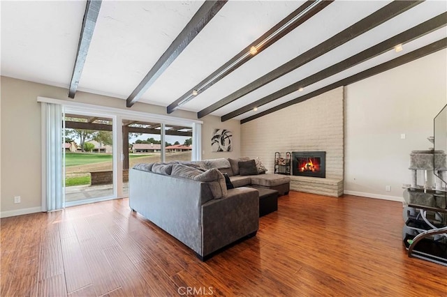 living room featuring baseboards, lofted ceiling with beams, wood finished floors, and a fireplace