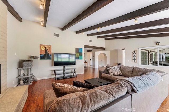 living room featuring a fireplace with raised hearth, baseboards, visible vents, and wood finished floors