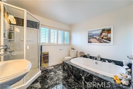 21651 Yucatan Ave, Woodland Hills, CA 91364 - bathroom featuring marble look tile flooring, a stall shower, a bath, a sink, and toilet